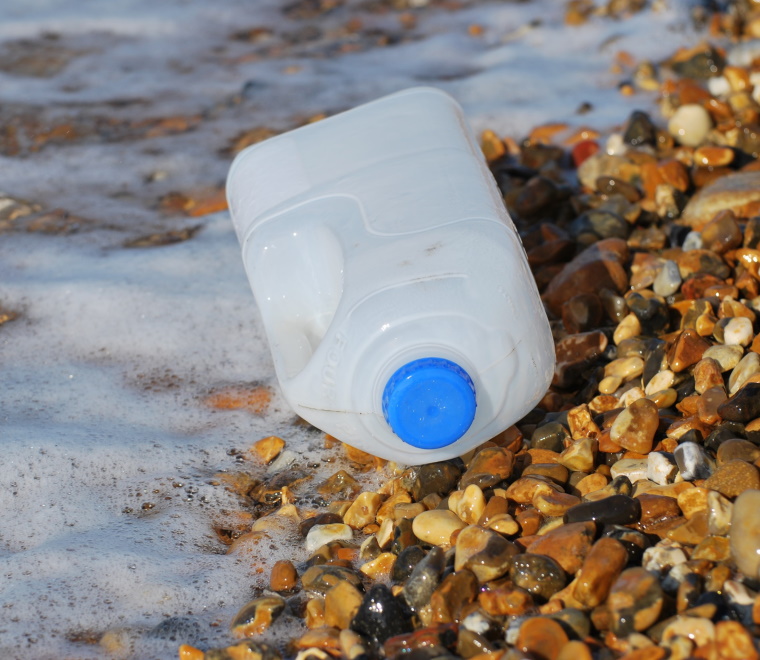 A photo of a plastic bottle washed up on a rocky beach